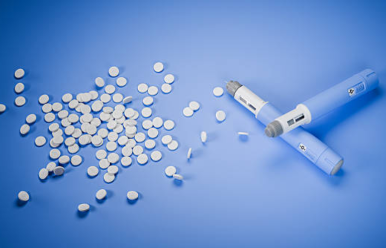 Oral tablets and injectable GLP-1 pen on a blue background representing oral semaglutide and subcutaneous Wegovy treatments.