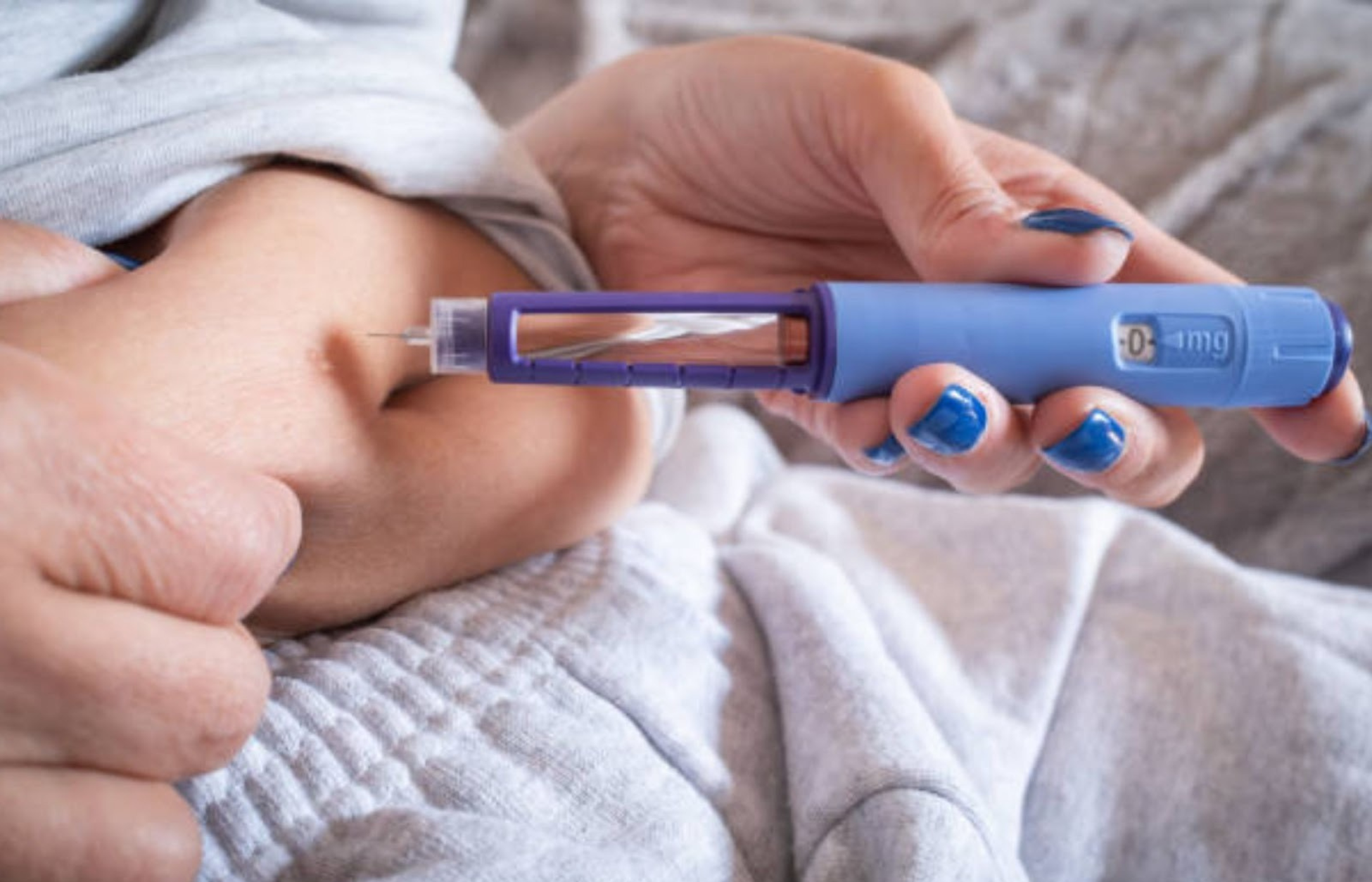 Person using a GLP-1 injection pen in the abdomen for diabetes or weight management treatment.