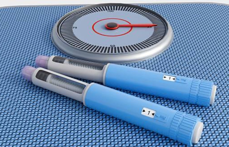 Two GLP-1 weight loss injection pens next to a scale on a blue surface, symbolizing medical weight management and progress tracking.