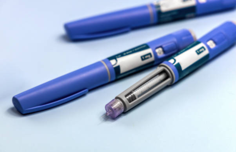 Close-up of blue GLP-1 injection pens with one pen showing a visible needle tip.
