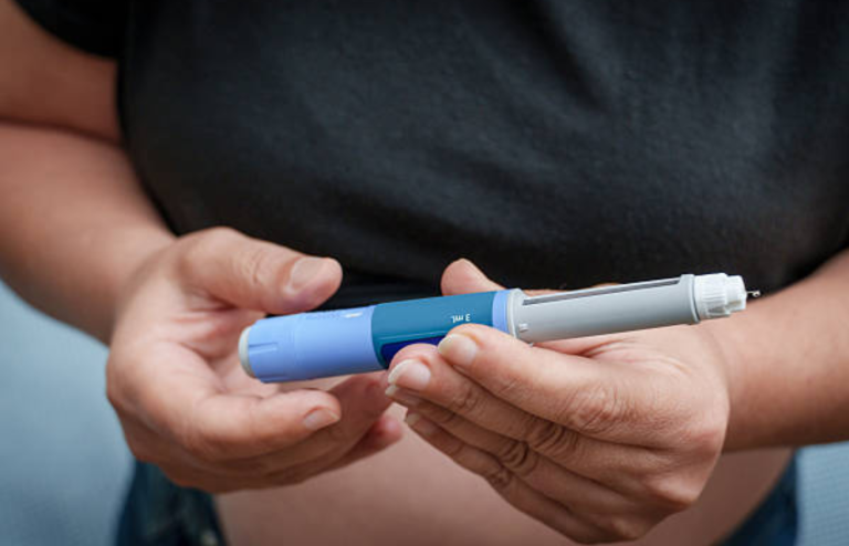Person holding a GLP-1 injection pen used for metabolic or diabetes treatment.
