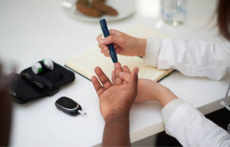 Healthcare professional checking a patient’s blood sugar level using a finger-prick test device at a clinic.