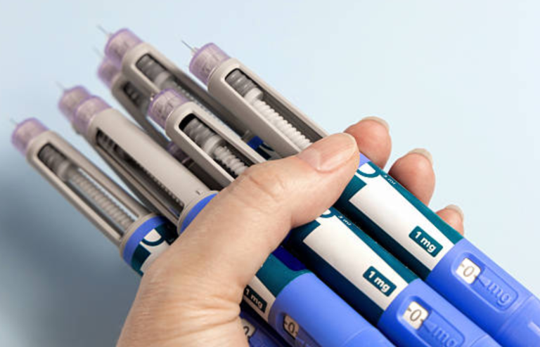Hand holding multiple GLP-1 injection pens used for weight loss and diabetes treatment.