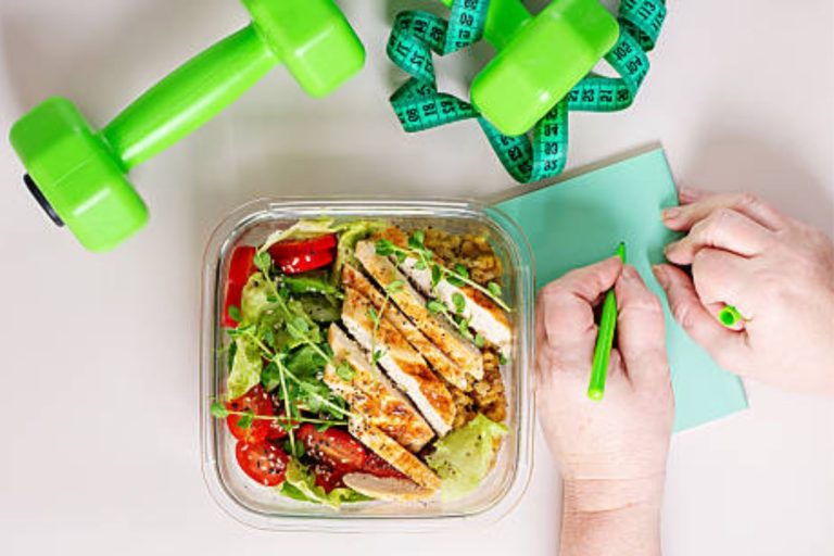 Healthy high-protein meal with chicken salad, dumbbells, and measuring tape representing a GLP-1 diet plan for weight loss.