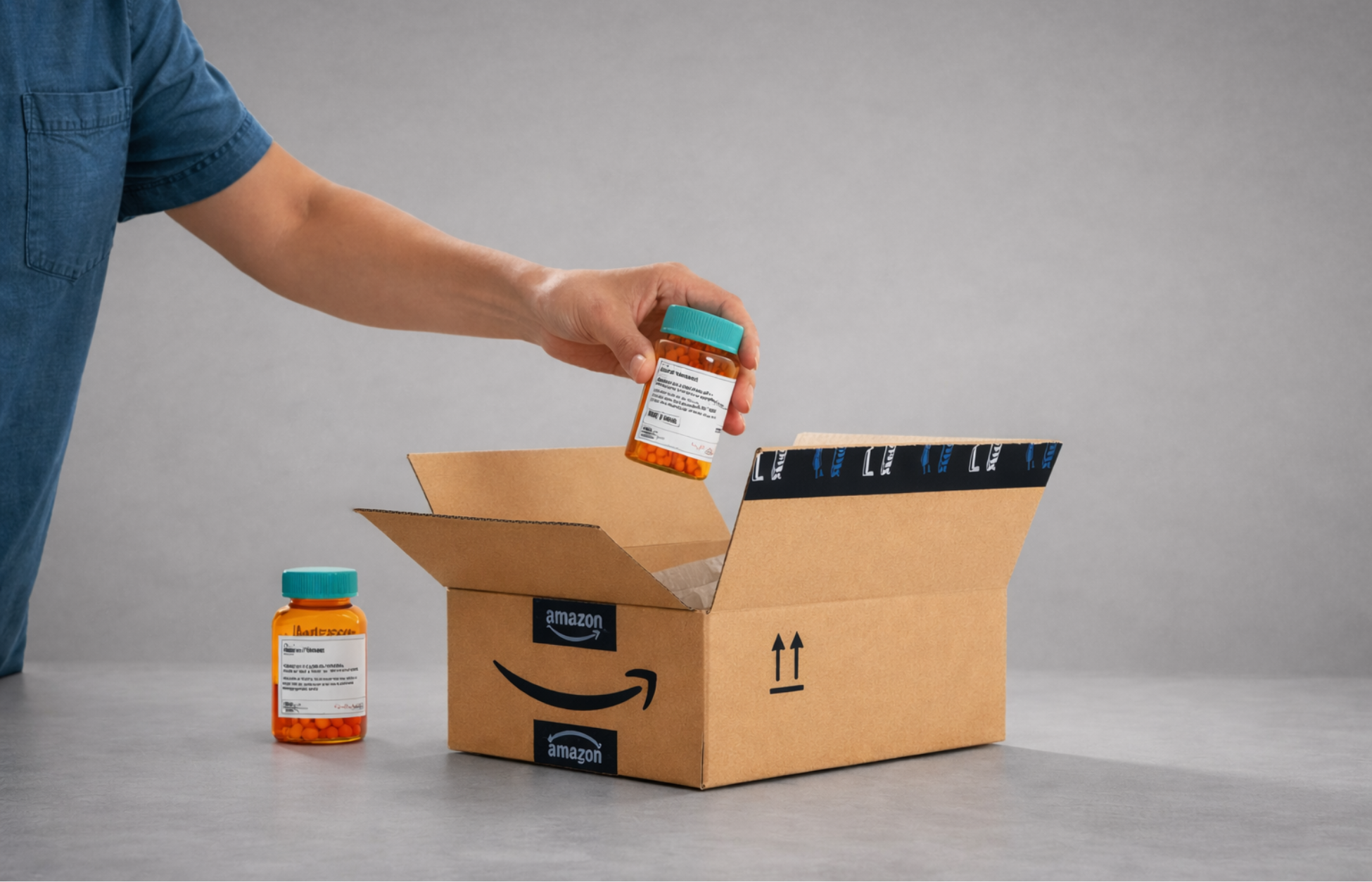 Hand placing a prescription pill bottle into an open Amazon-branded delivery box, with another bottle nearby.