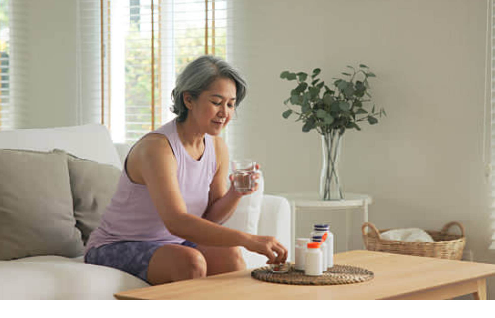 Woman taking medication with water while sitting on a couch at home