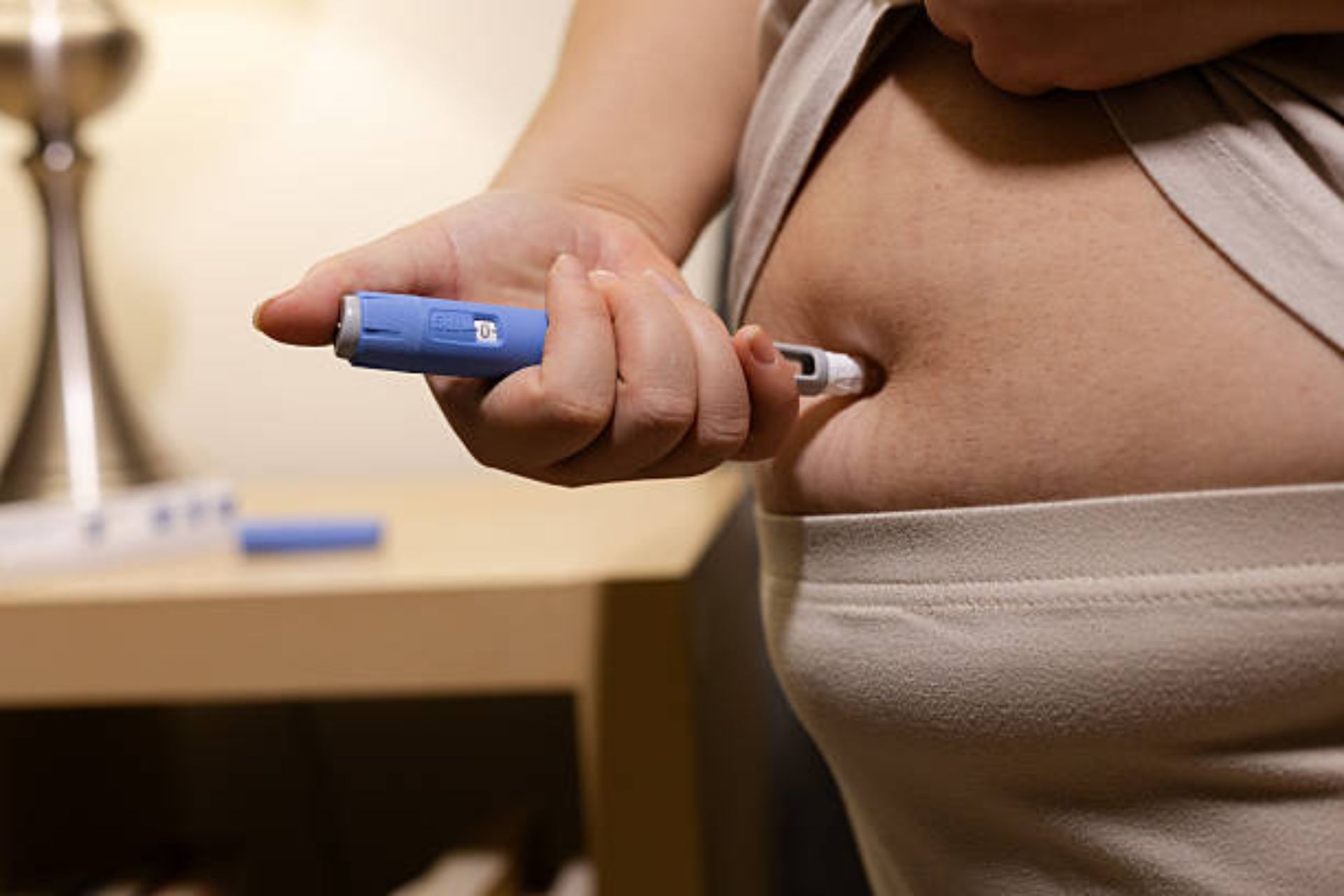 Person injecting GLP-1 medication into abdomen using pen device