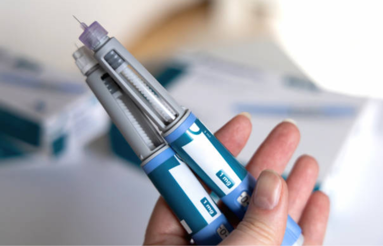 Hand holding two prefilled injection pens for Wegovy.