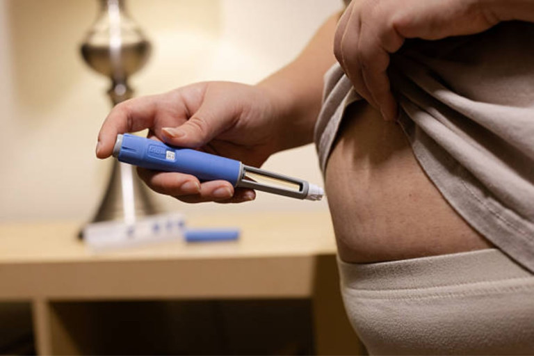 Close-up of a person injecting a GLP-1 medication into the abdomen using a pen device