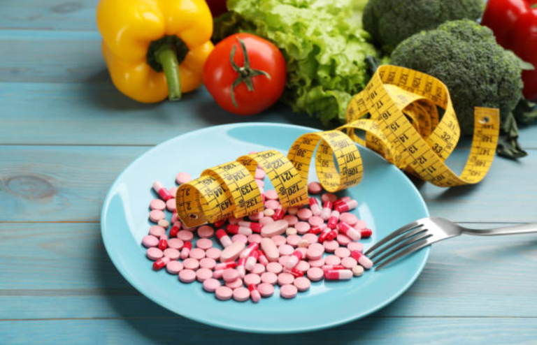 Plate of pills with measuring tape and fresh vegetables symbolizing weight loss and diet