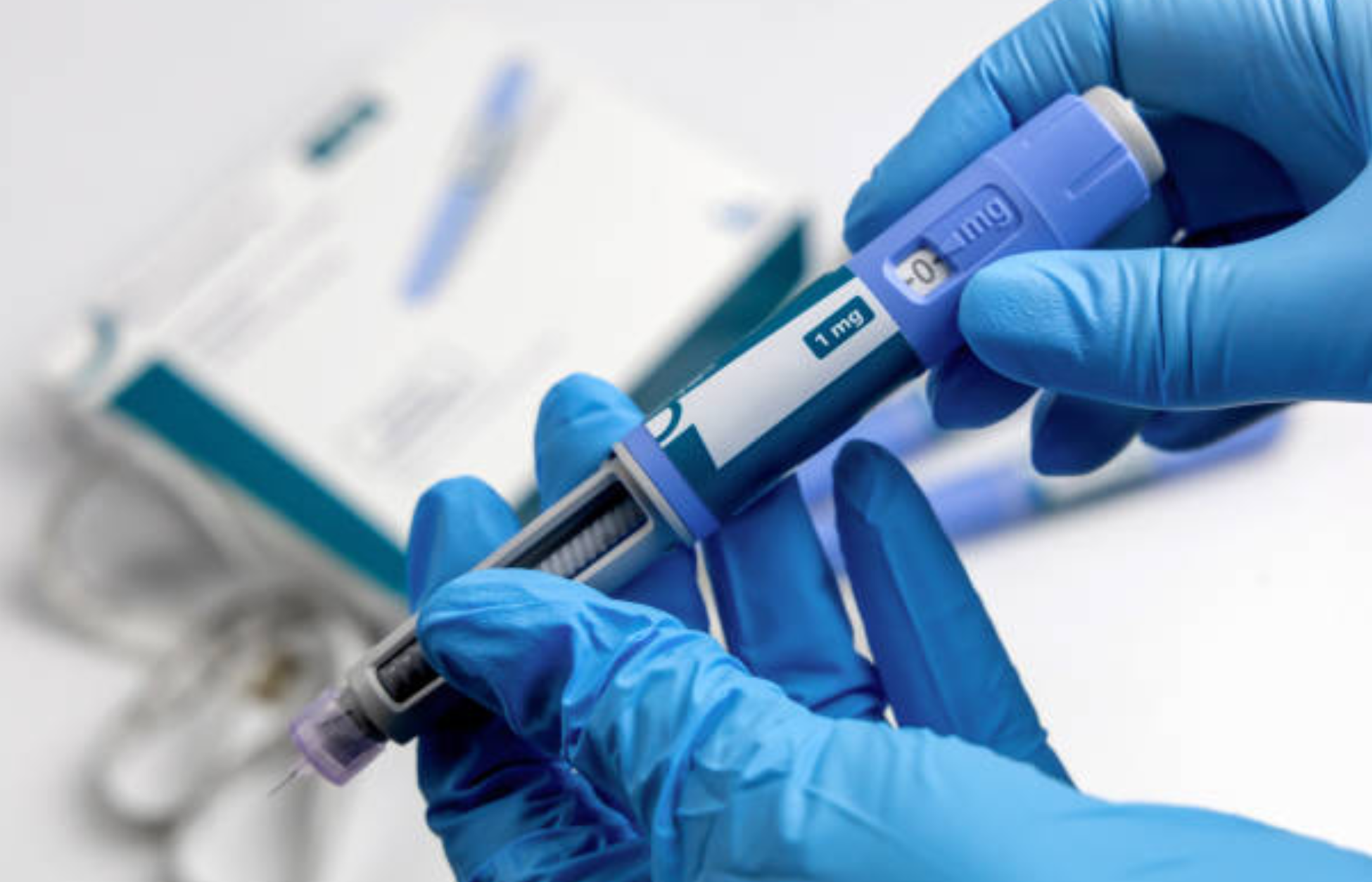 Gloved hands holding an Ozempic injection pen set to 1 mg dose