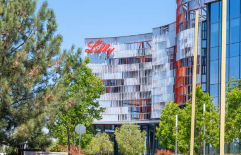 Eli Lilly office building with logo on a modern glass facade surrounded by trees