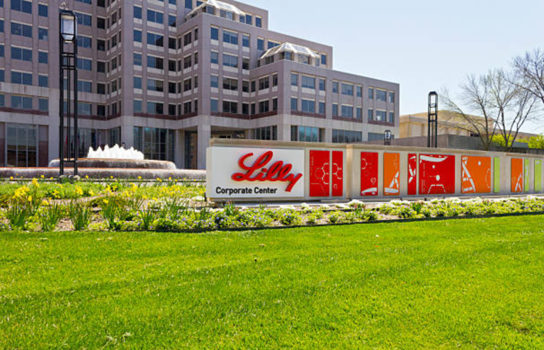 Exterior view of Eli Lilly corporate headquarters building with company signage and landscaped lawn.