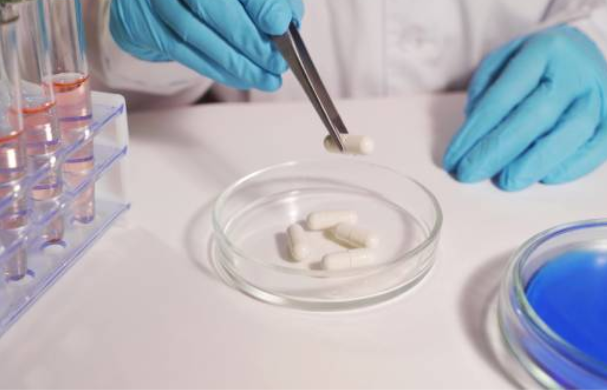 Scientist handling capsules with tweezers in a laboratory setting