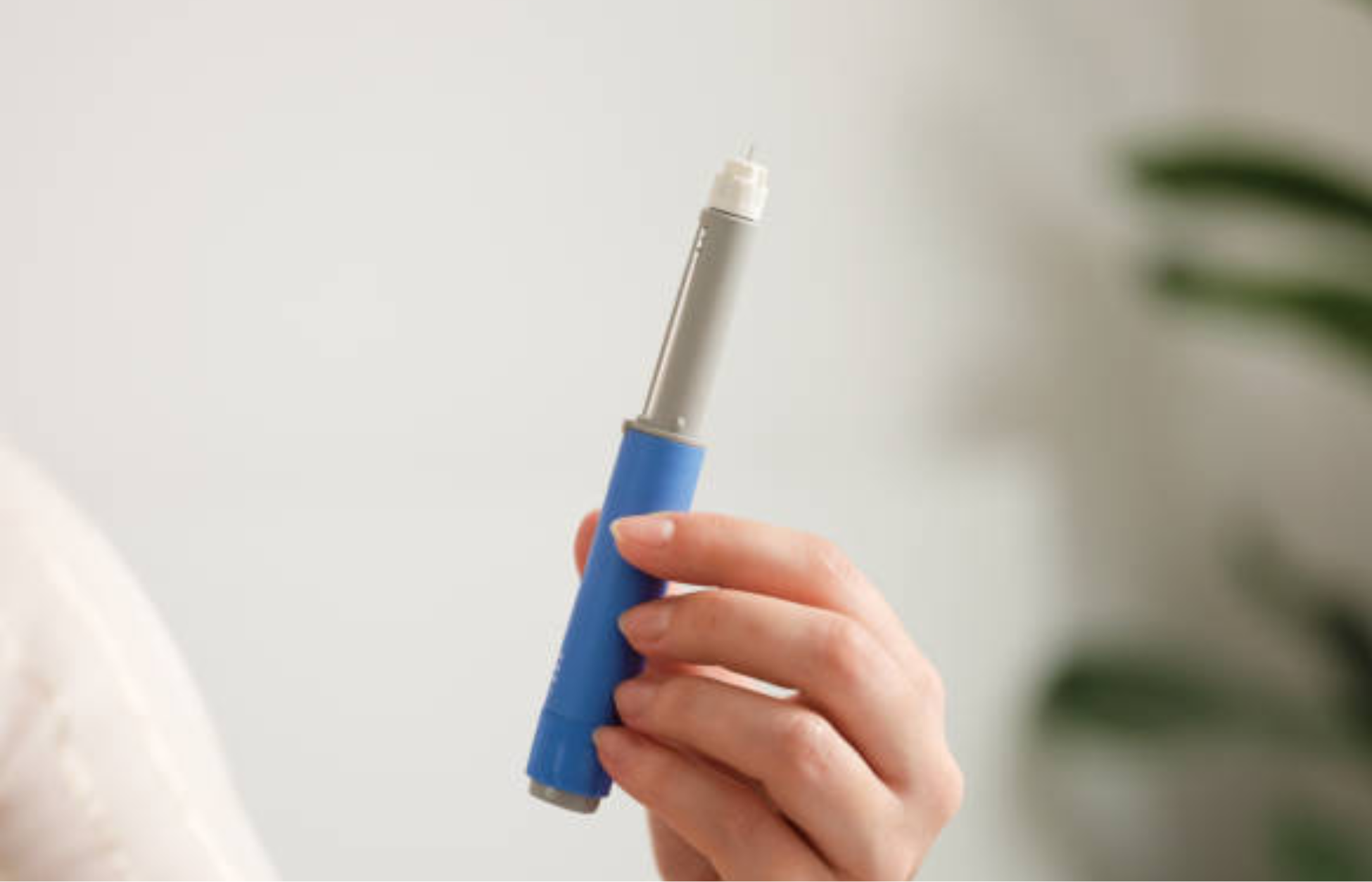 Hand holding a GLP-1 injection pen for weight management treatment.