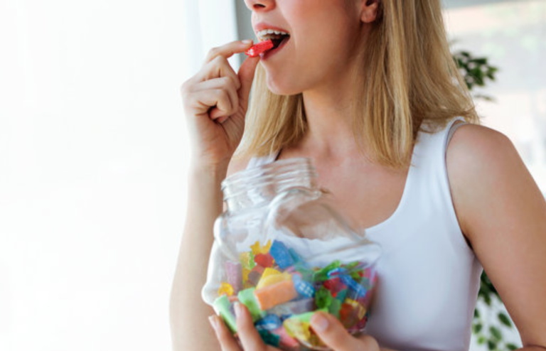 Woman eating candy from a jar, illustrating changing confectionery habits linked to GLP-1 therapy effects.