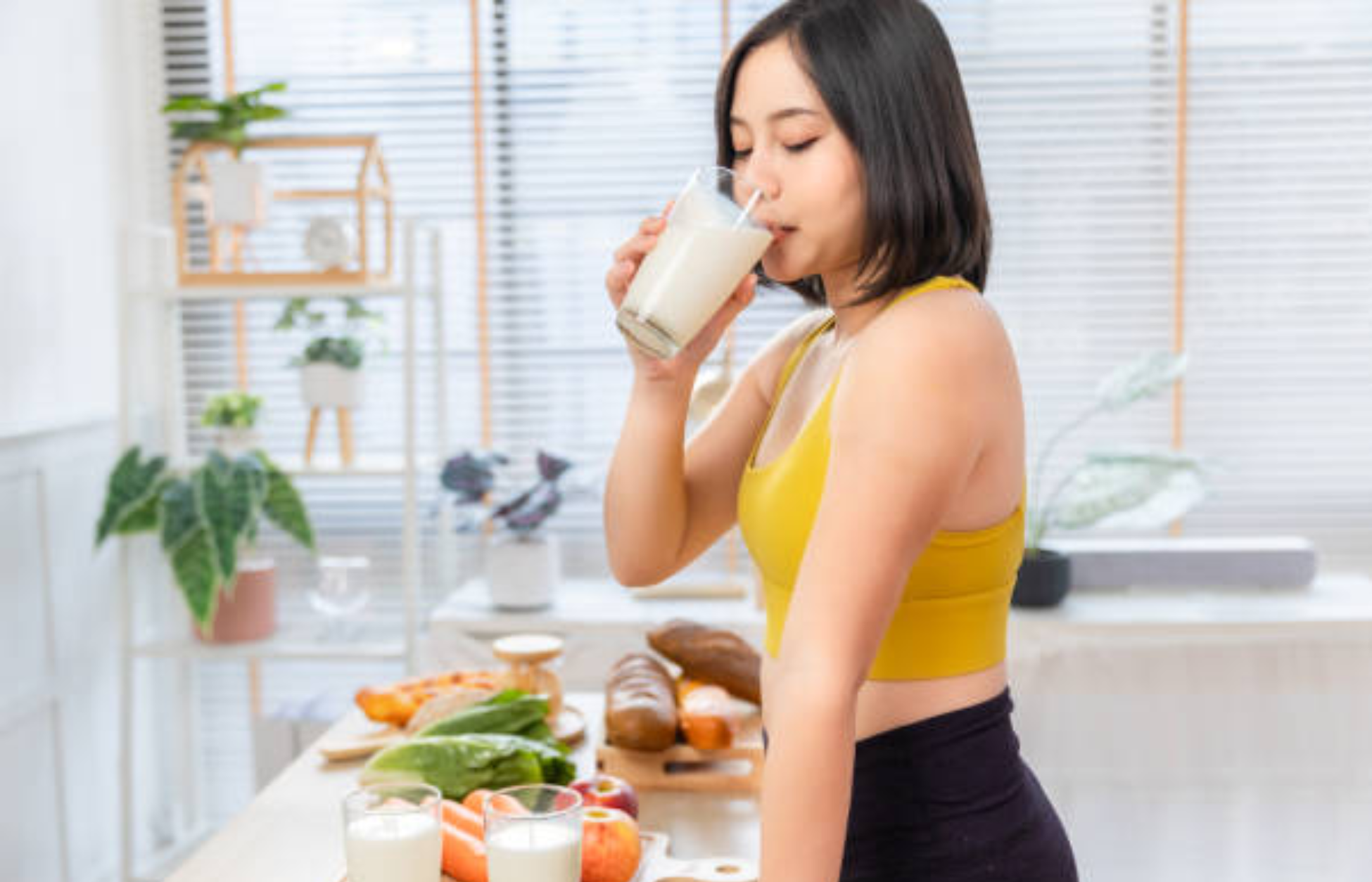 Woman drinking a meal replacement shake in a healthy kitchen.
