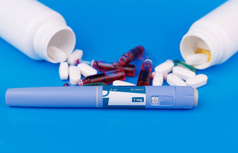 GLP-1 injection pen placed on a blue surface alongside scattered tablets, capsules, and medication bottles, representing modern weight-loss and diabetes treatments.