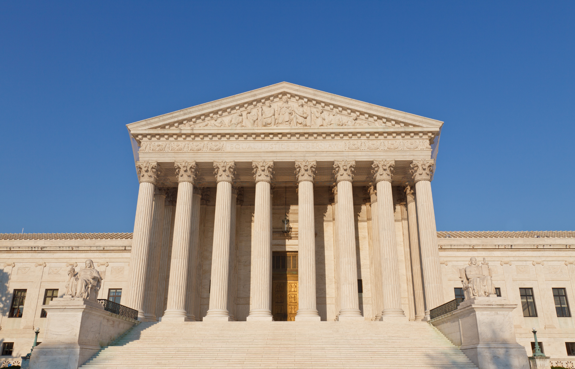 Front view of the U.S. Supreme Court building in Washington, D.C., featuring tall marble columns, wide staircase, and a clear blue sky overhead.