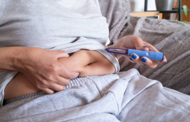 Person preparing to inject medication using a pen device in the abdomen