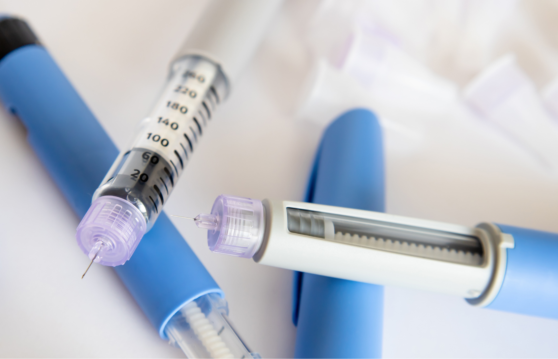 Close-up of injectable pens and a syringe used for GLP-1 medications in diabetes and weight management treatment.