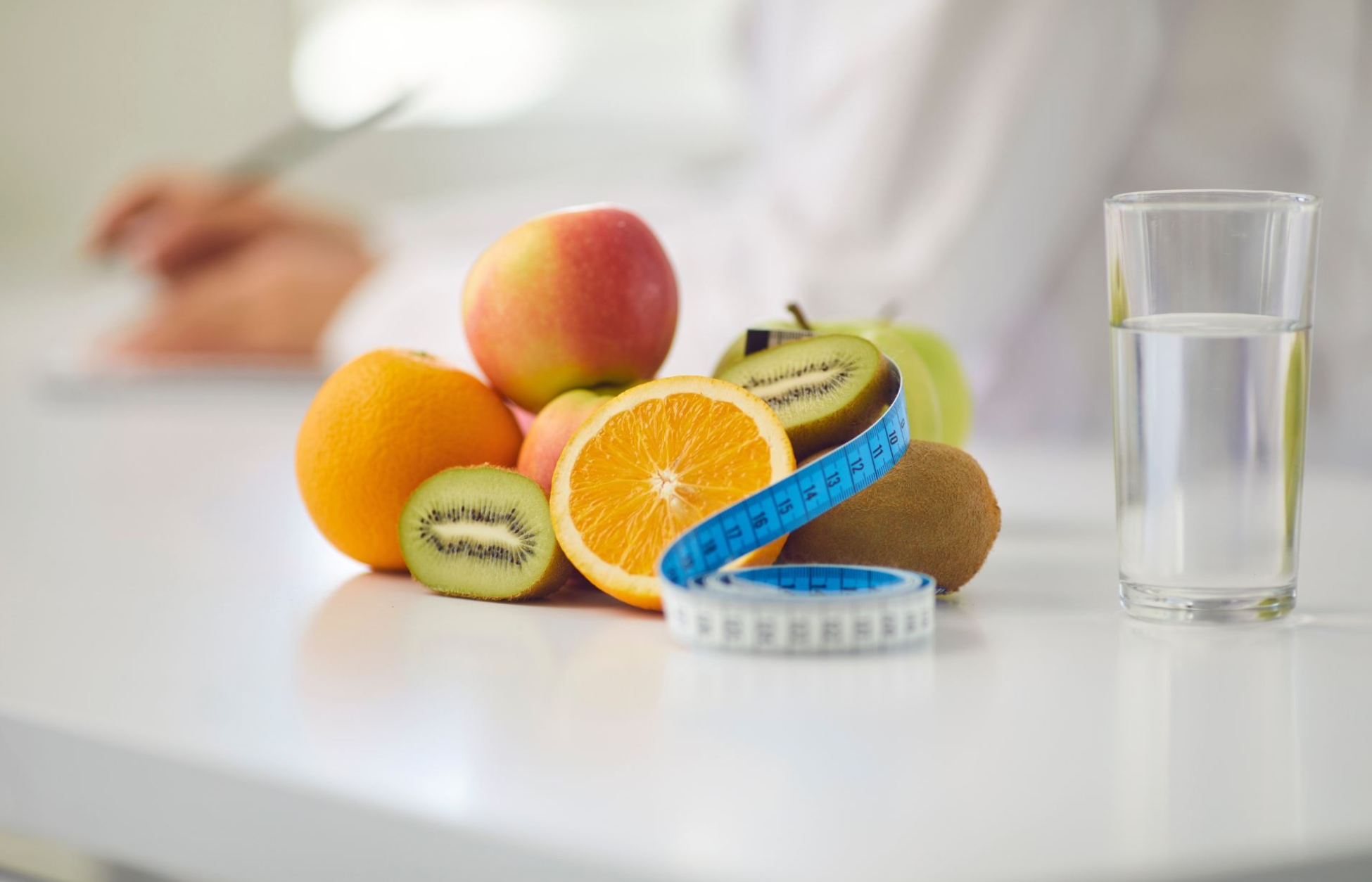Fresh fruits, a measuring tape, and a glass of water symbolize healthy eating and weight management alongside GLP-1 therapy.