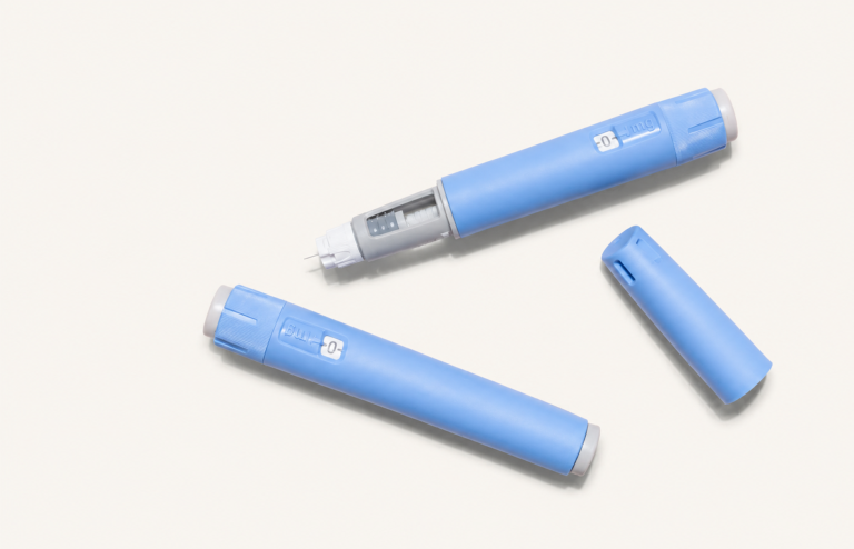 Two blue GLP-1 injection pens with one uncapped, showing the needle on a light background