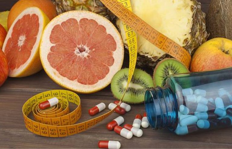 Weight-loss medication with healthy fruits, measuring tape, and capsules.