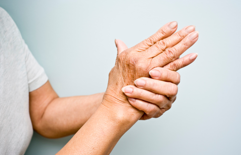 Person holding a painful hand, illustrating rheumatoid arthritis joint pain and stiffness.