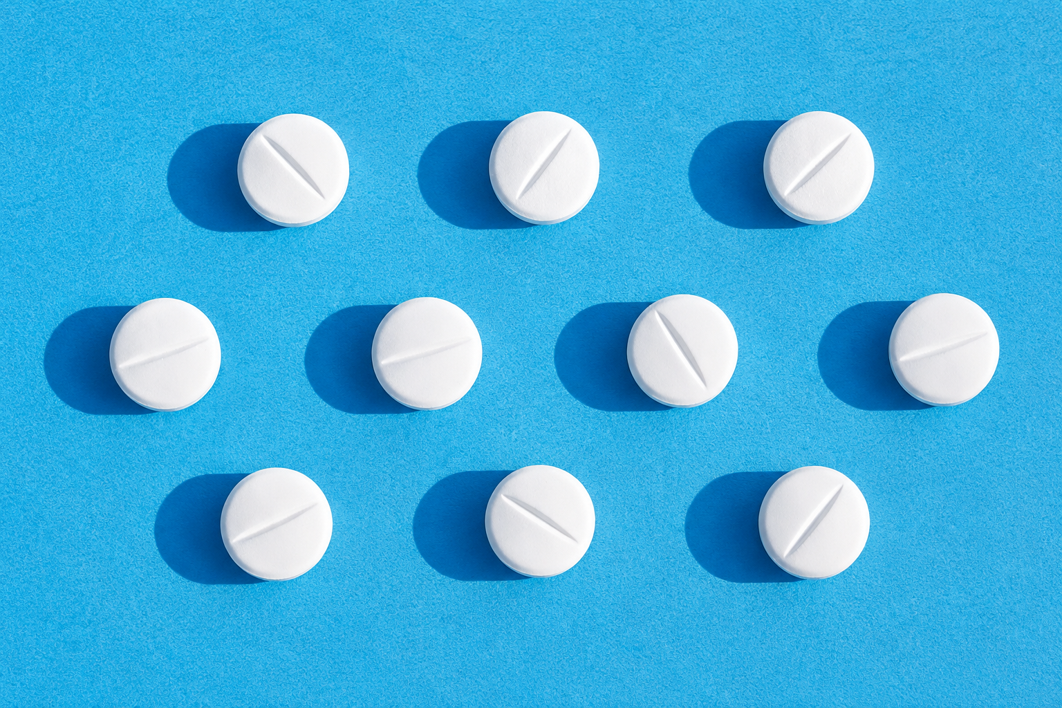 Multiple white round tablets arranged neatly on a blue background, representing oral prescription medications.