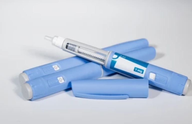 Blue GLP-1 injection pens arranged on a white background, representing diabetes and weight loss medication.