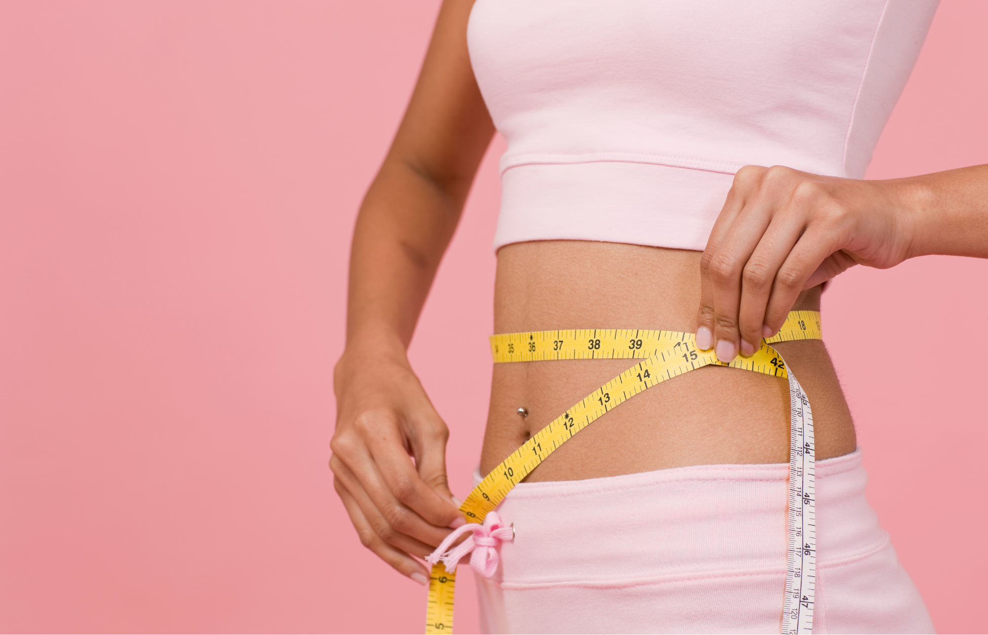 Woman measuring her waist with a tape measure, symbolizing GLP-1 weight loss and body transformation.
